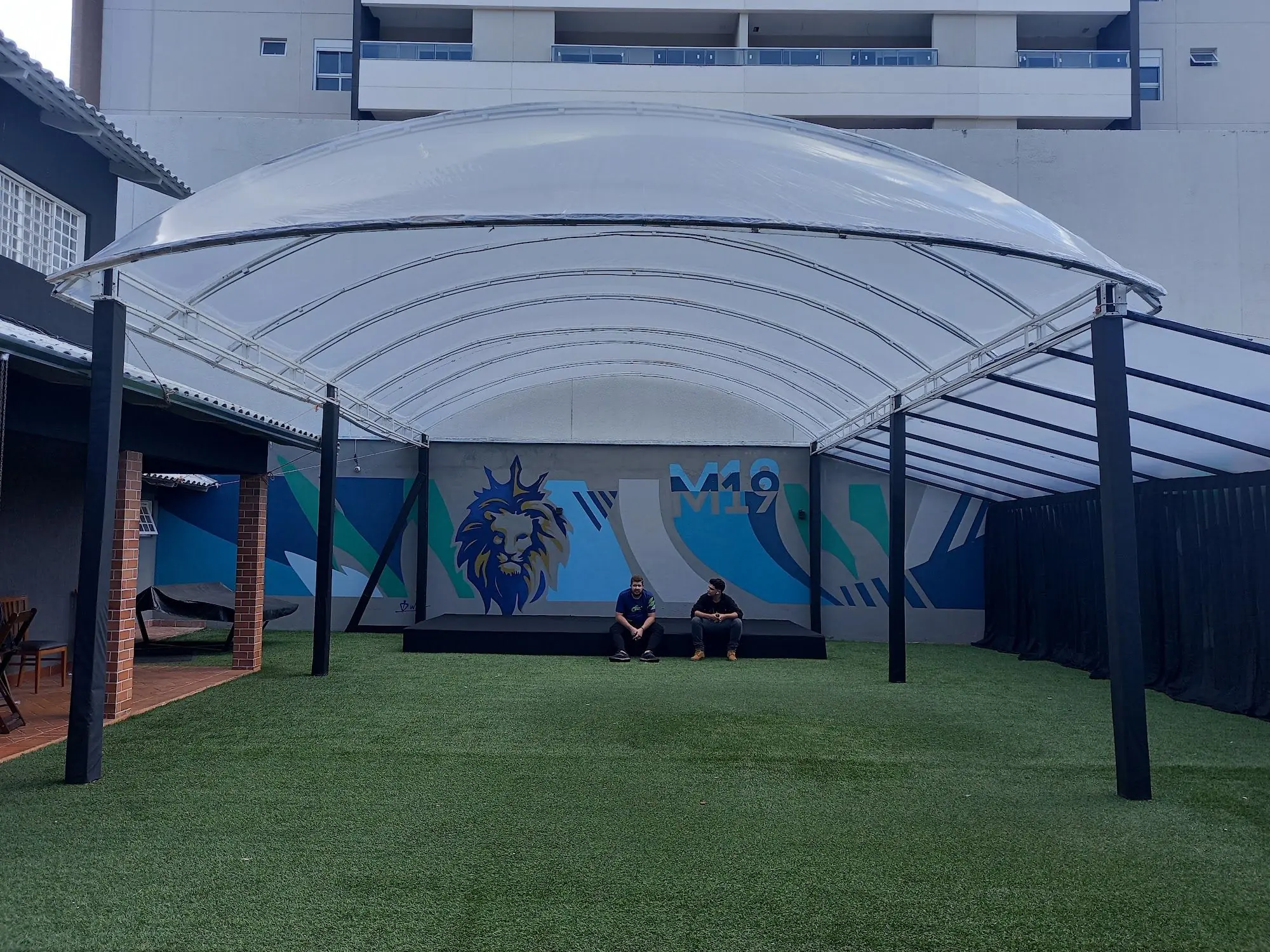 Área externa coberta com gramado sintético e mural