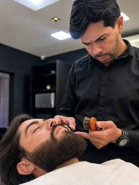 Barbeiro aplicando espuma com pincel na barba do cliente