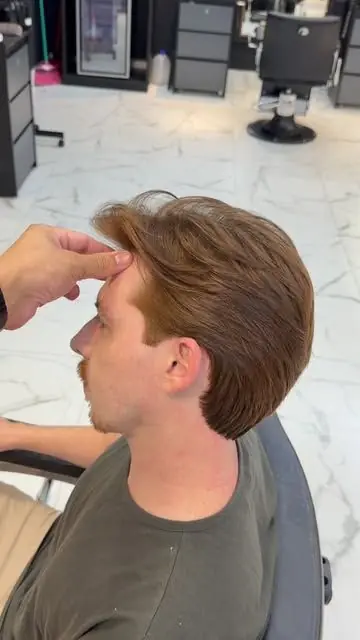 Barbeiro ajeitando o cabelo acobreado do cliente