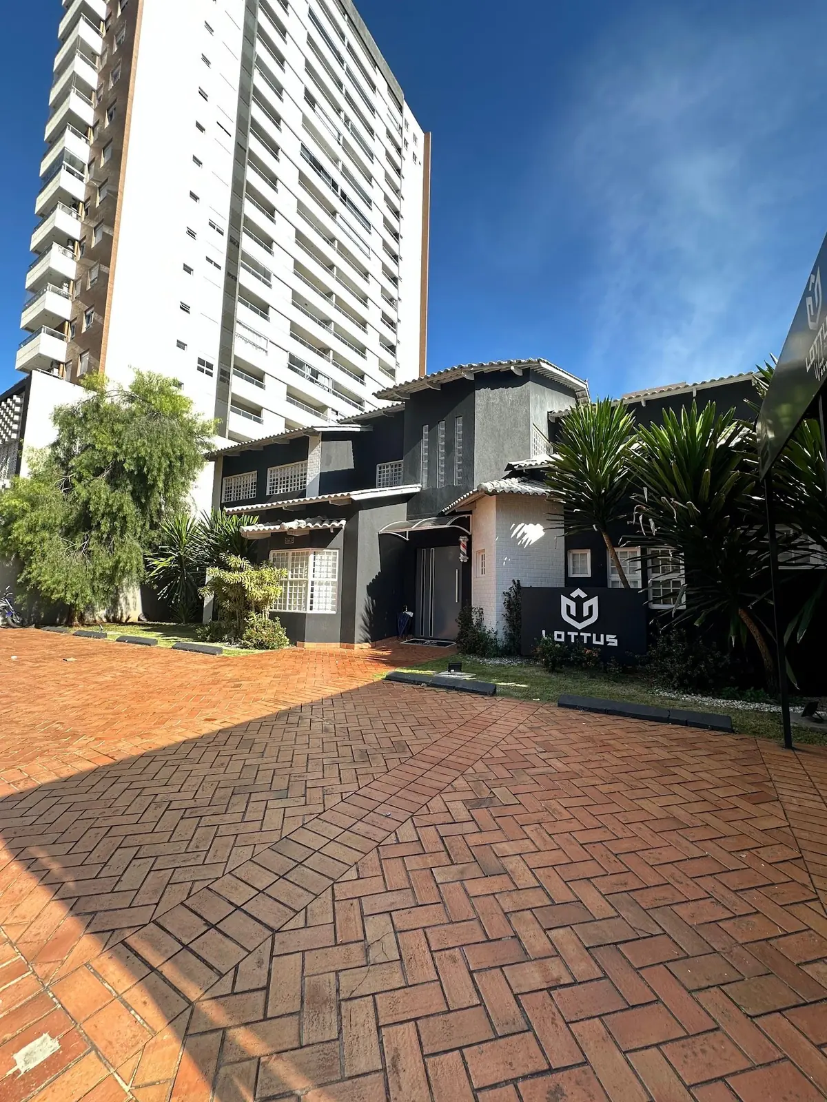 Fachada da Lottus durante o dia, com o letreiro e o calçamento de tijolos