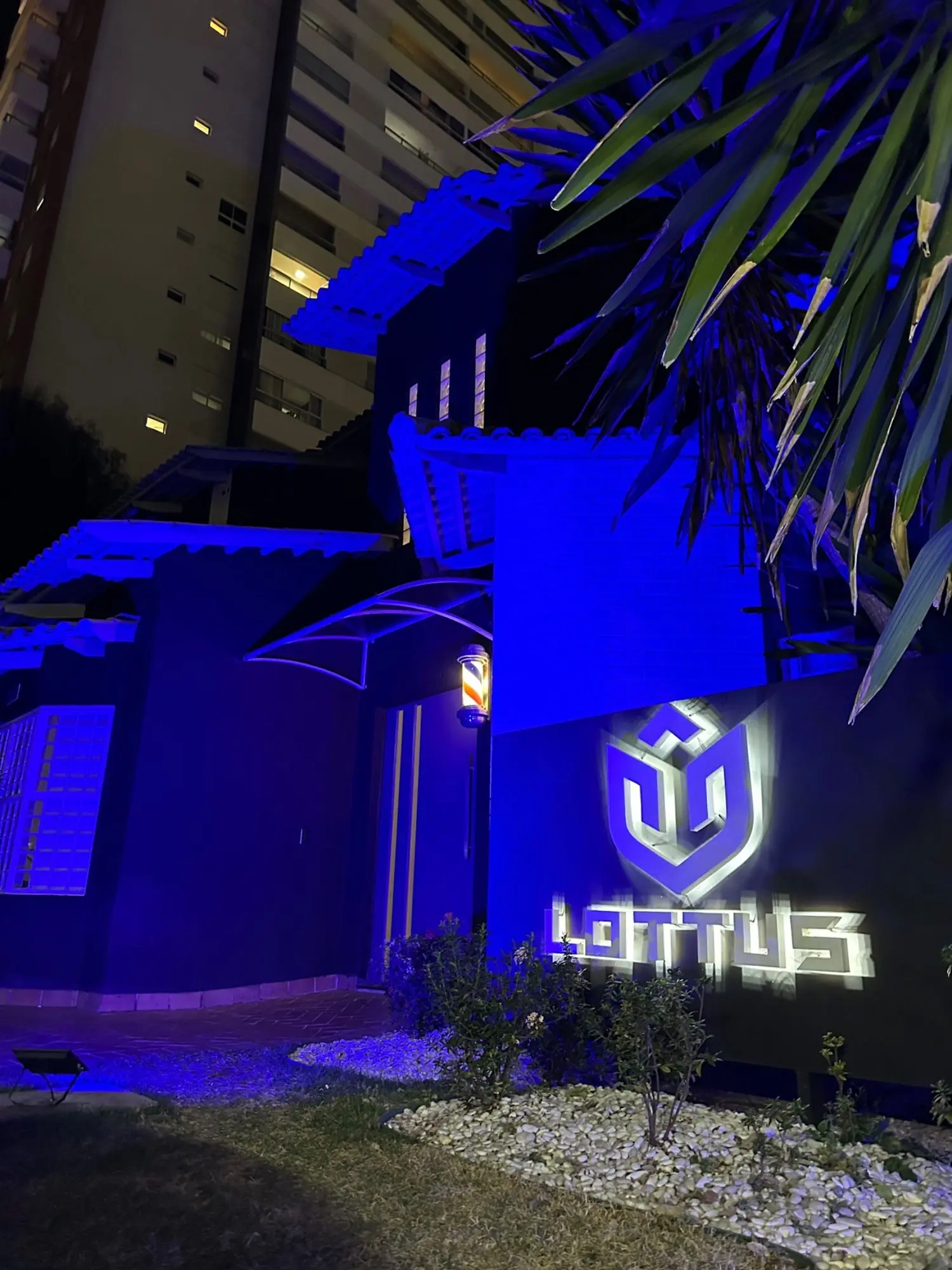 Letreiro da Lottus iluminado em azul na entrada, à noite