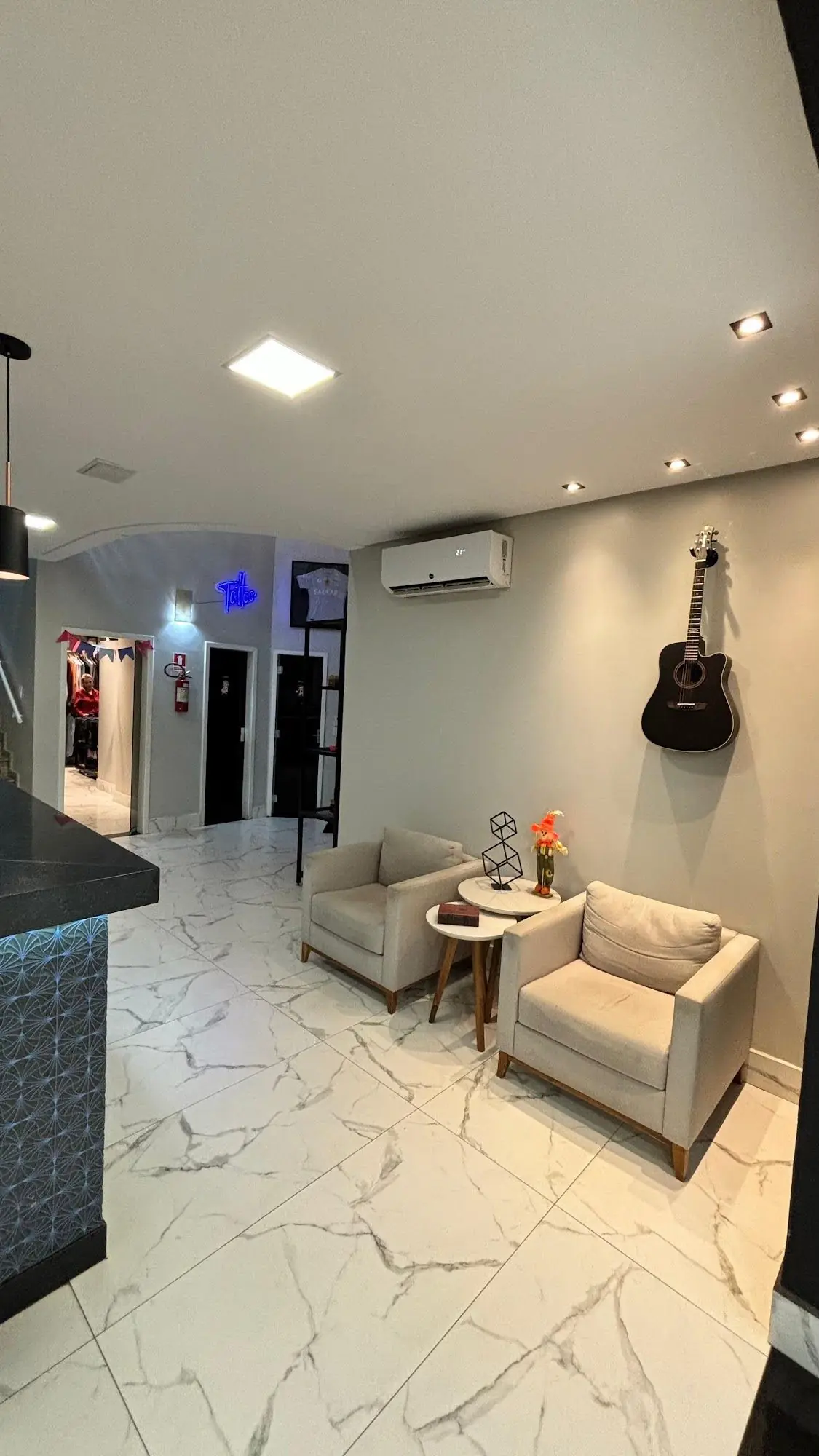 Recepção da Lottus com poltronas, violão na parede e piso de mármore